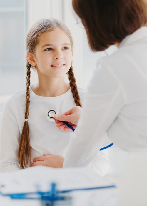 Family general practitioner examines child, listens lungs with stethoscope